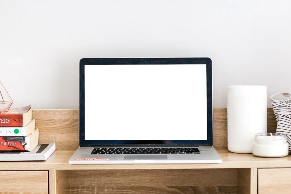 Open laptop and books on a light wooden desk