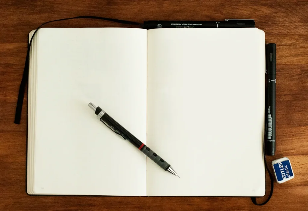 Open notebook with a pen resting across the pages