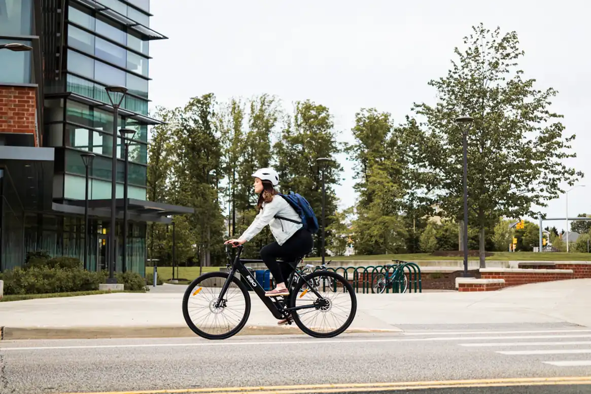Cyclist travelling past buildings and trees