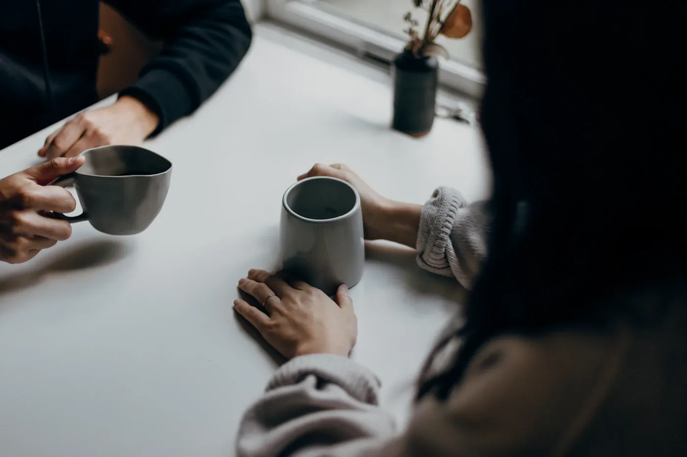 People talking over mugs at a cafe table