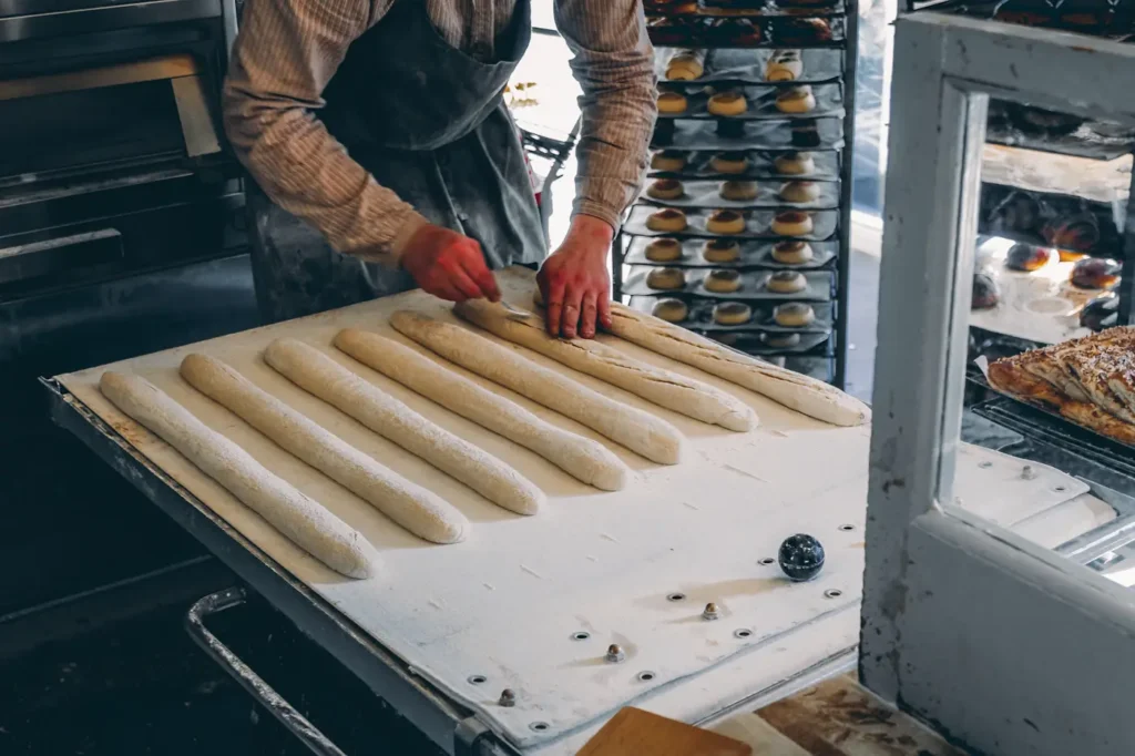 Baker shaping long loaves on a workbench