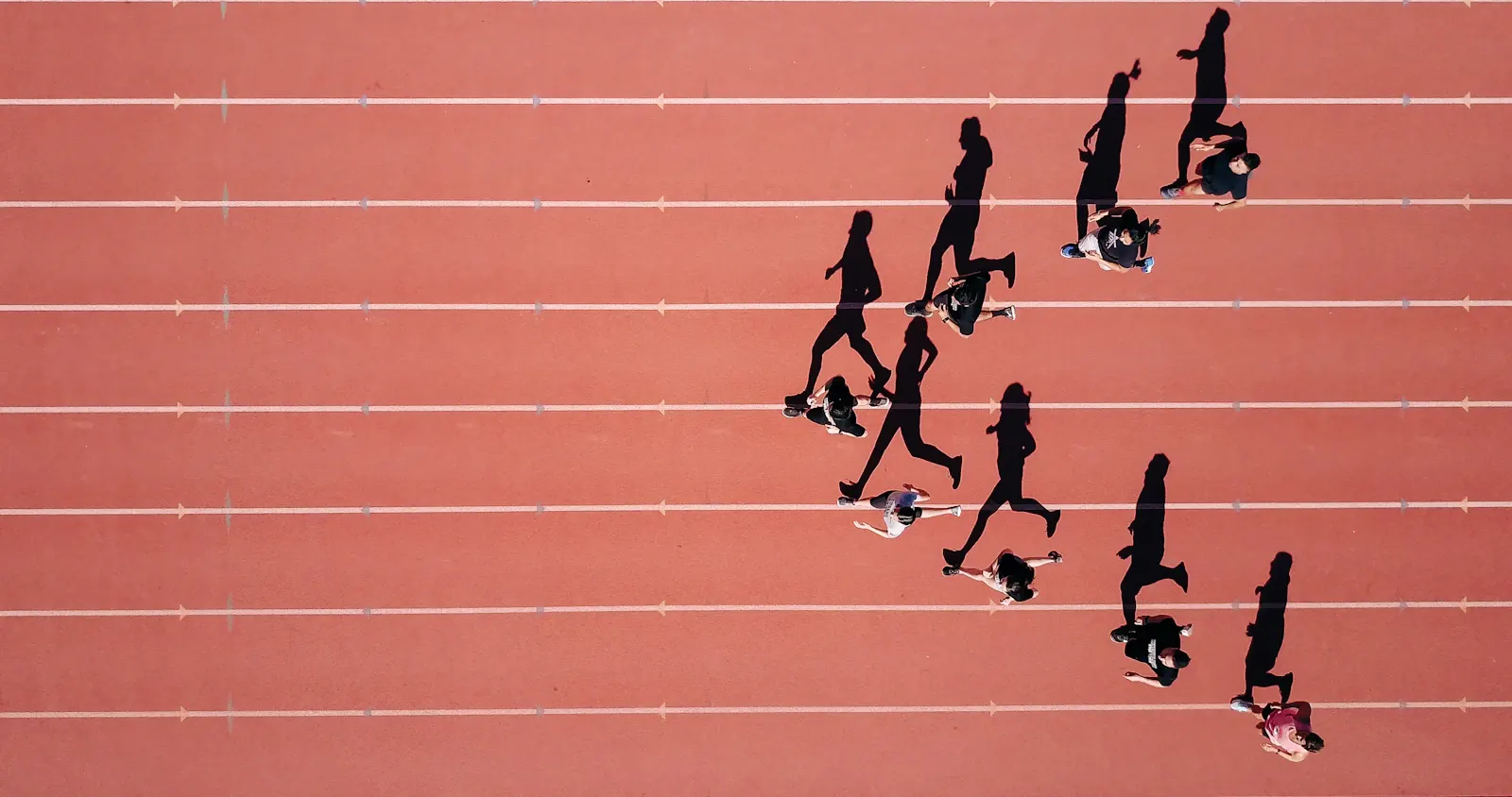 People moving along a red running track